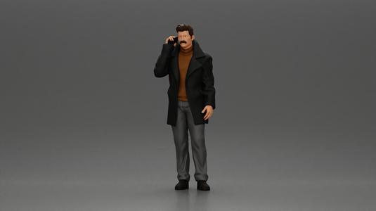 Turkish man in a coat with sweater standing talking on the mobile phone