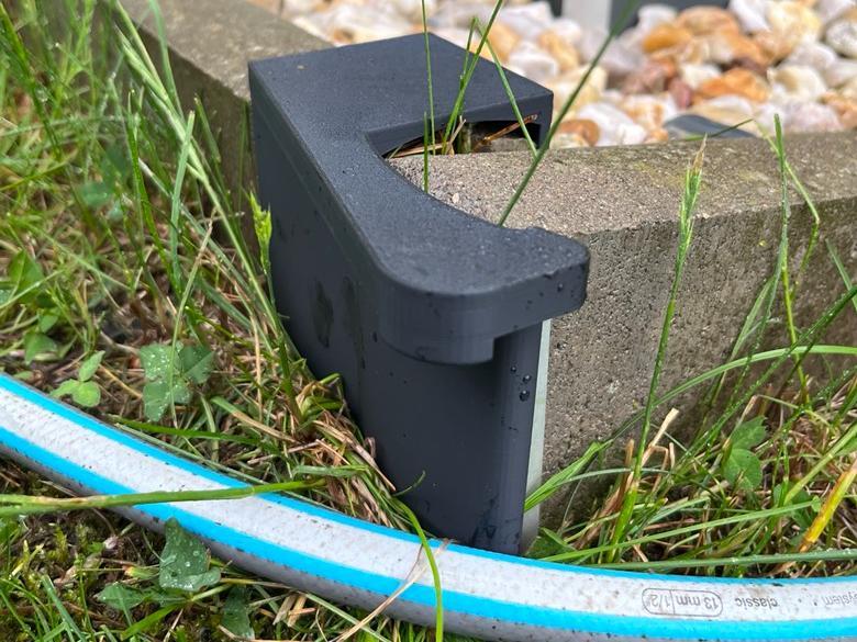 Hose guide for concrete curb corner
