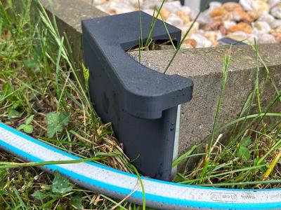 Hose guide for concrete curb corner