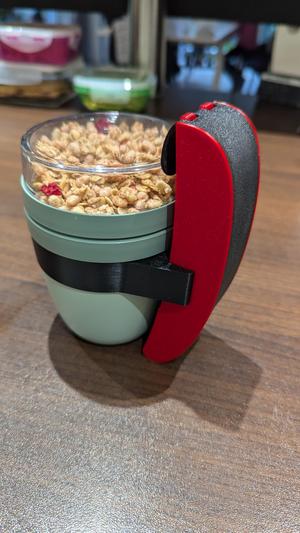 Spoon holder for yoghurt/muesli cup to go