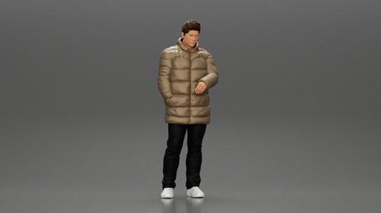 Man in long puffer jacket standing with his hand in his pocket lost in thought