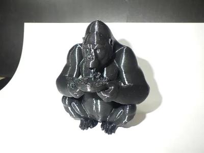 A Gorilla sitting eating pizza.   