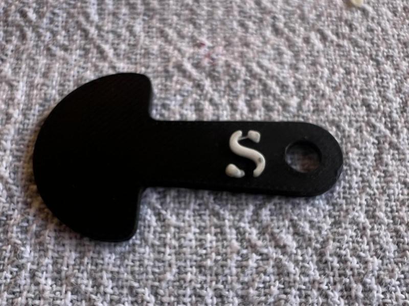 An Australian $1 trolley key with an 'S' on it