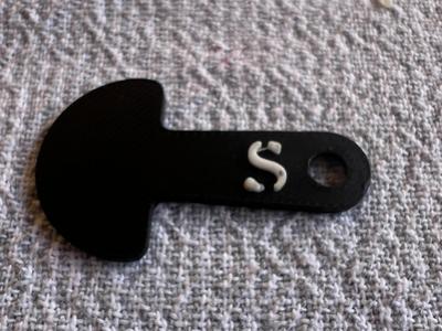 An Australian $1 trolley key with an 'S' on it